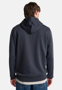 Dark navy hoodie with a smooth texture, featuring a large hood, ribbed cuffs and hem, and a relaxed fit, paired with denim jeans.