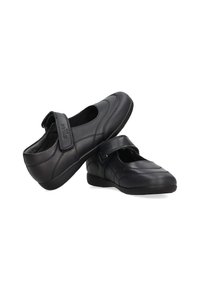 Zapatos de cuero negro con punta redondeada, una tira de Velcro en el empeine y un detalle texturizado en la parte superior. Suela plana de goma.