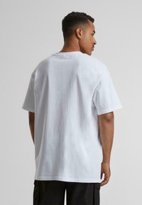 Hvid bomulds t-shirt med en afslappet pasform. Rund hals, korte ærmer og ensfarvet ryg med en glat tekstur. Ingen synlige logoer eller mønstre.