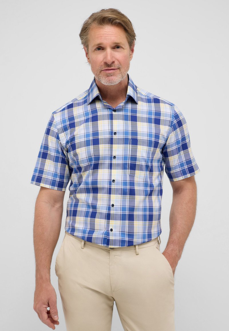 Korte mouwen geruite shirt in blauw, geel en crème. Heeft een knoopsluiting aan de voorkant, een kraag en een klein borstzakje. Gladde stofstructuur.