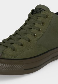 Υψηλή ελιά πράσινη Converse αθλητικό παπούτσι με πάνελ από σουέτ και ύφασμα, ταιριαστά κορδόνια και σκοτεινή λαστιχένια σόλα και μύτη.