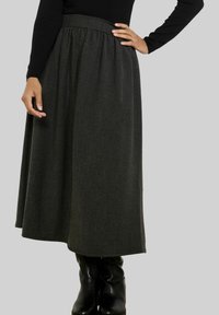 Dolga, temno siva krila iz teksturiranega blaga. Ima zbrano oblikovano pasnico in sega čez kolena; kombinirana z črnimi škornji.