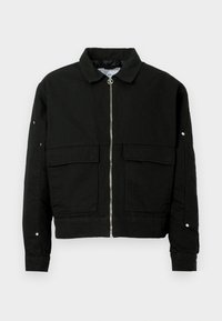 Chaqueta negra de tejido resistente, con cierre de cremallera en el frente, dos bolsillos frontales y cuello con solapas. Incluye detalles de botones en las mangas.