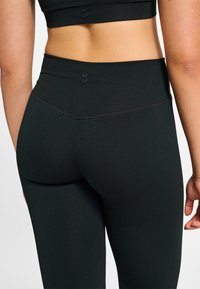 Zwarte leggings met hoge taille, gemaakt van rekbaar materiaal, met een textuurpatroon en subtiele chevrondetails bij de tailleband.