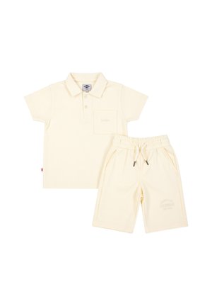Polo à manches courtes couleur crème avec poche poitrine, associé à un short assorti à taille élastique et cordon de serrage.