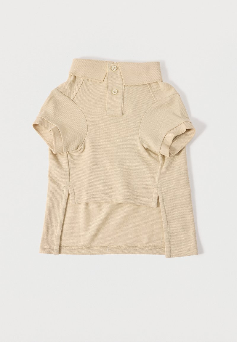 Polo beige à manches courtes avec deux boutons, col côtelé et fentes latérales, posé à plat sur un fond clair.