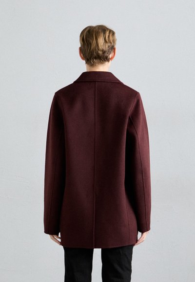 Cappotto in misto lana bordeaux con silhouette sartoriale, colletto a punta, maniche lunghe e taglio dritto sul retro. Texture liscia.