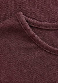 Burgundská látka s měkkou texturou, s kulatým výstřihem. Viditelné švy a jemný pletený vzor zvyšují atraktivitu designu.