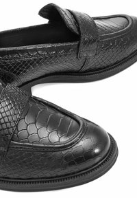 Czarne skórzane mokasyny z teksturowanym wzorem wężowej skóry, okrągłym noskiem i ozdobnym paskiem na górze. Gładka podeszwa.