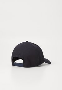 Gorra azul marino con visera curvada, tela suave, cierre ajustable tipo snapback y orificios de ventilación en los laterales. Vista trasera mostrada.