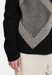 Gestickter Pullover in Schwarz mit einem cremefarbenen Rauten-Muster. Verfügt über eine gerippte Textur, lange Ärmel und einen verkürzten Schnitt.