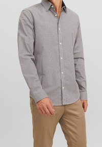 Mans långärmad skjorta i ett litet rutmönster, främst vit och marinblå, med knappad krage och standardmanschetter. Tillverkad av bomull.