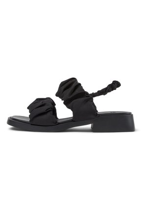 I sandali neri presentano un design con tessuto morbido arricciato, punta aperta, suola piatta e una cinghia posteriore intrecciata per una vestibilità regolabile.