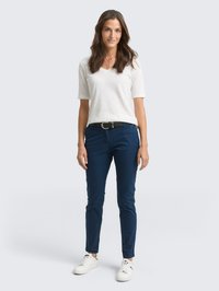 Witte, korte mouwen v-hals t-shirt gecombineerd met marineblauwe, slim-fit broek. Gekozen met witte sneakers. Eenvoudig ontwerp, geschikt voor casual wear.