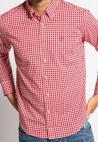 Chemise en coton à carreaux rouges et blancs avec manches longues, dotée d'une poche poitrine unique et de boutons dorés.