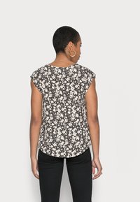 Blusa de estampado floral com fundo escuro, mangas curtas, bainha arredondada e corte relaxado, confeccionada em tecido leve e texturizado.