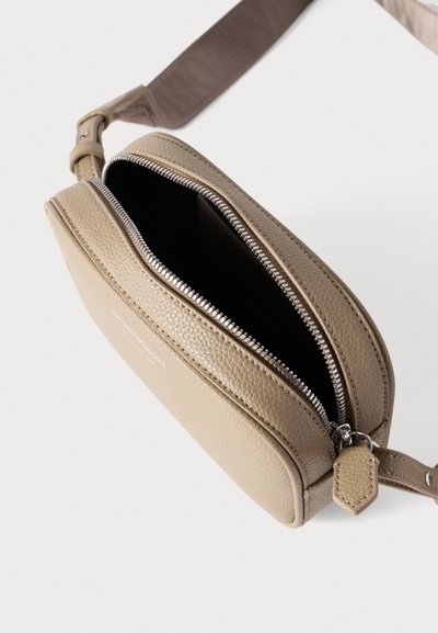 Μπεζ δερμάτινη τσάντα ώμου με υφή, διπλά φερμουάρ σε δύο διαμερίσματα και καφέ ρυθμιζόμενο λουράκι. Το εσωτερικό είναι επενδυμένο με μαύρο ύφασμα.