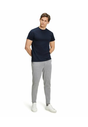 Marineblaues Kurzarm-T-Shirt, kombiniert mit hellgrauen, eng anliegenden Jogginghosen und weißen Sneakern. Das Outfit zeichnet sich durch ein schlichtes Design und glattes Material aus.
