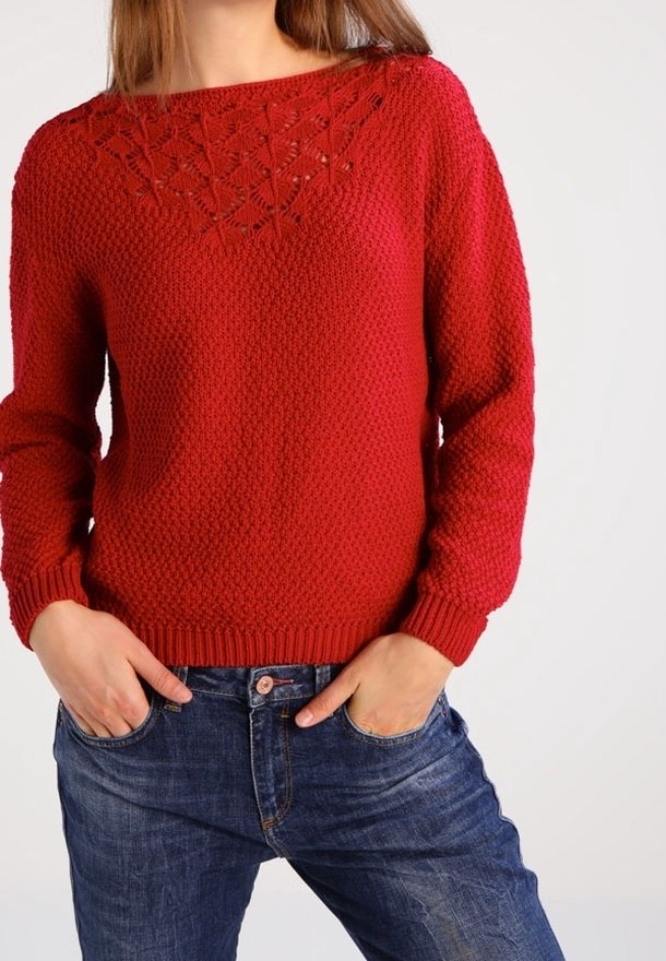 Maglioncino rosso lavorato a maglia con corpo testurizzato e dettaglio in pizzo al collo, dotato di maniche lunghe e polsini a coste. Indossato con jeans blu.