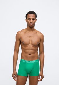 Zöld pamut boxeralsó, színtartó fazonnal és rugalmas derékrésszel, amelyen a "TOMMY HILFIGER" logó fehér betűkkel látható.