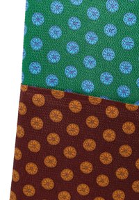 Dwa teksturowane materiały: jeden zielony z niebieskimi okrągłymi wzorami, a drugi brązowy z pomarańczowymi kropkami, oba z powtarzającymi się wzorami.