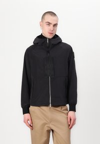 Black lightweight jacket with a zip front, hood, and chest pocket. Features elastic cuffs and a textured fabric for a sleek appearance.