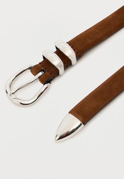 Ceinture en daim marron avec boucle en métal argenté, deux passants et une pointe en métal sur un fond clair.