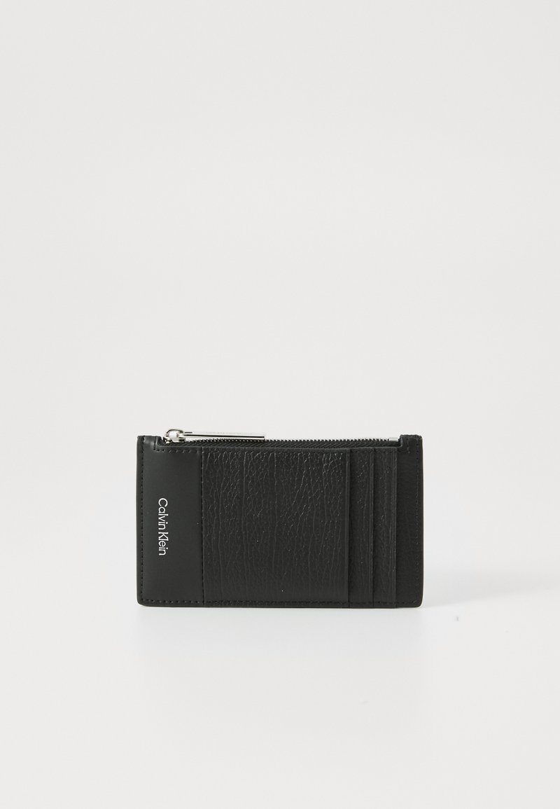 Portefeuille en cuir noir avec une finition texturée, plusieurs emplacements pour cartes, une poche zippée et un logo embossé à l'avant.
