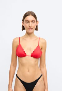 Κόκκινο μπικίνι τοπ με κυματιστές άκρες, ρυθμιζόμενες τιράντες και λεία υφή; συνδυασμένο με μαύρα μίνιμαλ σλιπ.