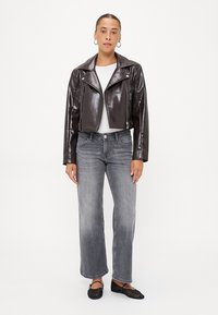 Brun fusk läder kort bikerjacka med dragkedjor, kombinerad med grå vida jeans och svarta flats. Enkel vit skjorta under.