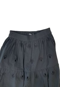 Gonna nera a strati realizzata in tessuto leggero, con dettagli in ricamo floreale e una cintura elastica per una vestibilità comoda.
