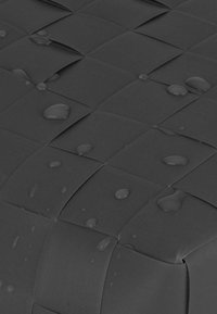 Schwarzes gewebtes Material mit einer strukturierten Oberfläche. Mehrere Wassertropfen sind auf der Oberseite sichtbar, was seine wasserdichte Qualität unterstreicht.