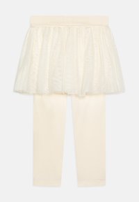 Ensemble deux pièces comprenant une jupe crème opaque avec un voile de tulle transparent et des leggings crème ajustés assortis. Taille élastique incluse.
