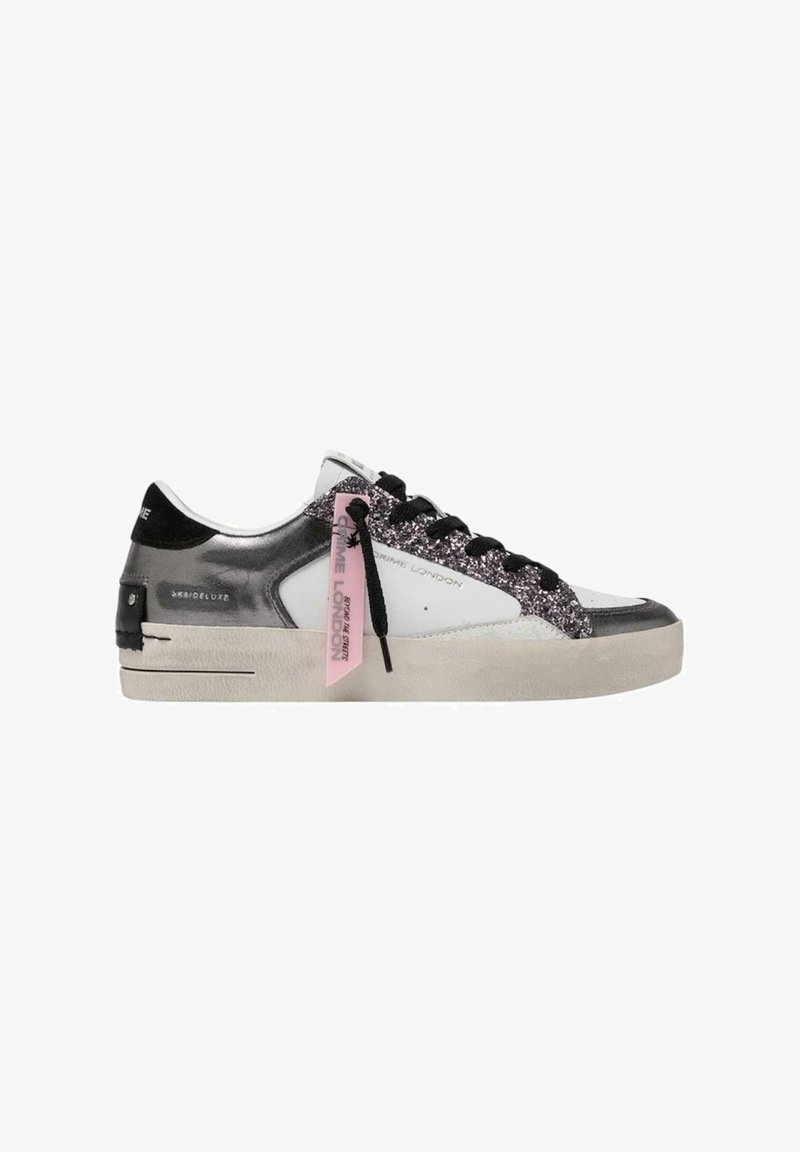 Sneaker bianco con accenti metallici argento, materiale nero e luccicante nel tallone e nella linguetta, caratterizzato da lacci neri e un'etichetta rosa.