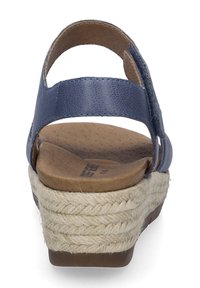 Marineblaue Sandale mit einem strukturierten Lederoberteil, einer Holzsohle und einem gewobenen Jute-Plateau-Absatz. Offene Rückseite und seitliche Riemen zur Unterstützung.