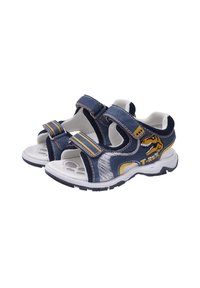 Sandales en denim bleu avec deux sangles ajustables en Velcro, semelles en caoutchouc blanches, et un graphique de dinosaure sur le côté. Accents en jaune et gris.