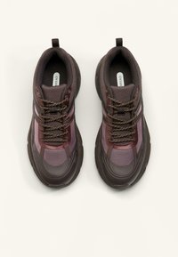 Sport shoes in dark purple and brown mesh with textured panels, lace-up design, and rubber soles. Features reinforced toe and heel areas.