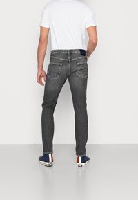 Slim-fit, tmavě šedé džíny se dvěma zadními kapsami. Vyrobené z denimu, s jemnou texturou a koženým logem značky na pásku.
