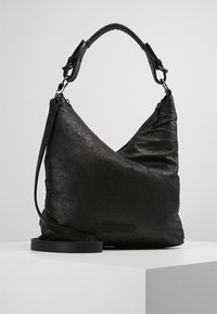 Musta nahkainen hobo-laukku, jossa on teksturoitu pinta, epäsymmetrinen muotoilu, säädettävä olkahihna ja vetoketjukiinnitys yläosassa.