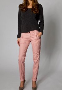 Ljusrosa bomullsbukser med smal passform och uppvikta cuffs, i kombination med en mörkgrå stickad tröja, båda stylade med taupe-höga klackar.