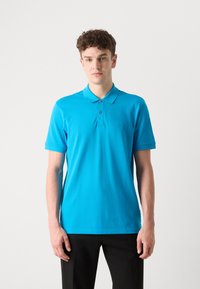 Turkis polo skjorte laget av bomull, med krage, korte ermer og en liten merke-logo på venstre bryst.