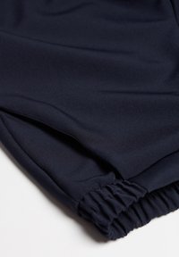 Pantaloni sportivi blu navy realizzati in un tessuto morbido e elasticizzato, con una vita elastica e polsini arricciati per il massimo comfort.