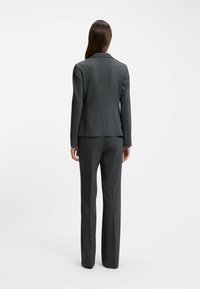 Donkergrijze op maat gemaakte suit met een aansluitende blazer met een subtiele streeppatroon en rechte broek. Gladde textuur, slank ontwerp.