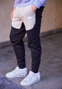 Nike sweatpants med en färgblockdesign i grått och marinblått. Gjorda av mjukt tyg, med sidofickor och ribbade muddar. Bärs med vita sneakers.