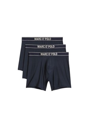 Tres pares de calzoncillos bóxer azul oscuro con el logo blanco de "MARC O' POLO" en las cinturas elásticas apilados sobre un fondo blanco.