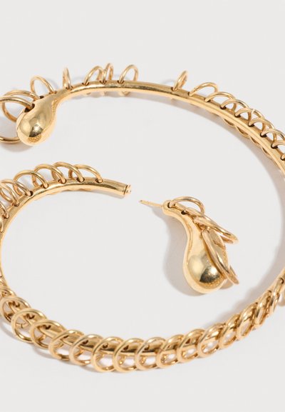 Σκουλαρίκια κρίκοι σε χρυσό τόνο με σχέδιο πλεξίματος αλυσίδας και λεία, κυρτά σχέδια σε σχήμα σταγόνας, σε λευκό φόντο.