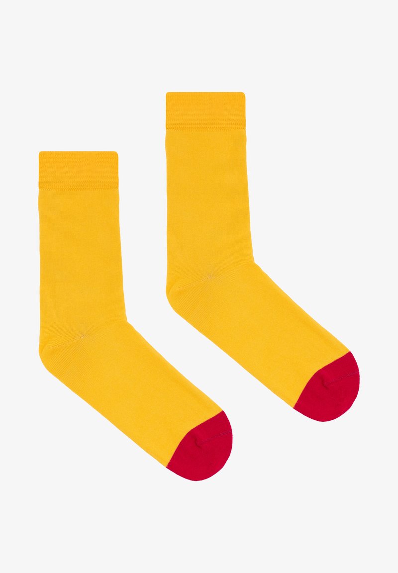 Żółte bawełniane skarpetki o jednolitym wzorze, z czerwonymi palcami. Gładka tekstura, długość do połowy łydki i prążkowane wykończenie na górze zapewniające pewne dopasowanie.