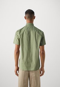 Korte mouwen overhemd in lichtgroene stof met een gestructureerde kraag, achterkant yoke detail en een gladde textuur, gecombineerd met beige broek.