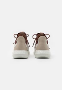 Beige a hnědé tenisky s texturovaným svrškem z nubuku, polstrovaným opatkem, hnědými akcenty a odpovídajícími hnědými tkaničkami. Gumová podrážka s protišmykovým vzorem.