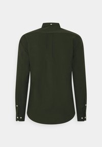 Chemise à manches longues vert foncé avec poignets boutonnés et pli au dos, vue de dos sur un fond clair uni.